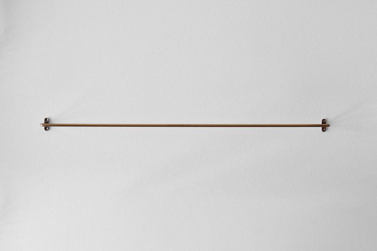 a white wall with a metal bar hanging from it's center and two hooks on the side