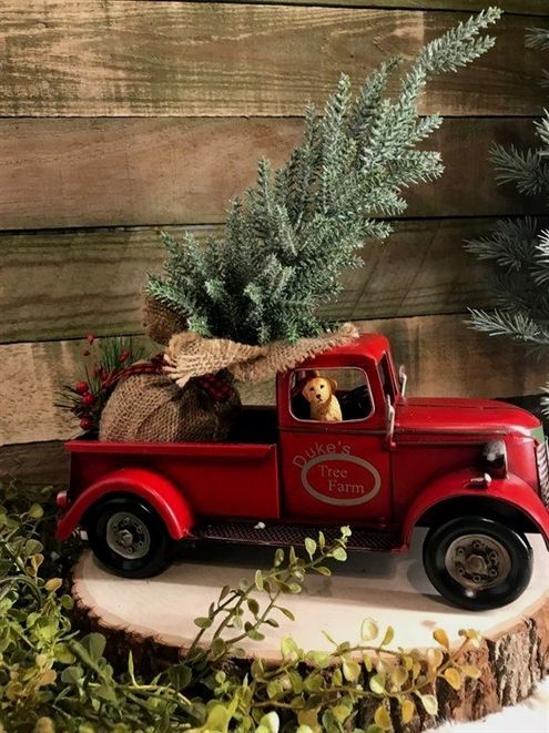 an old red truck with a christmas tree in the back and pine cones on top