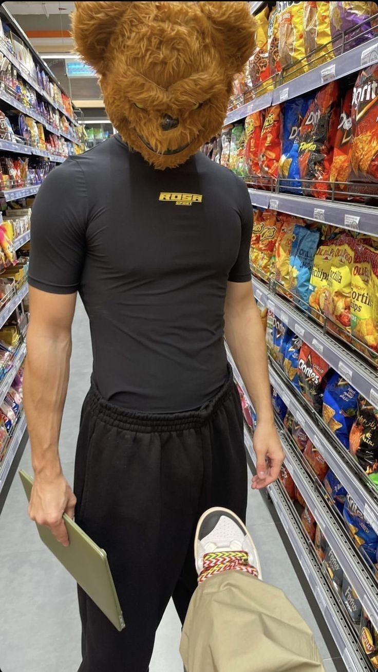 a man wearing a teddy bear mask in a grocery store aisle with his back to the camera