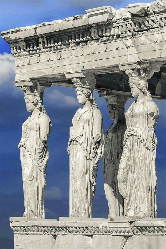 some statues are standing on the side of a building with blue skies in the background