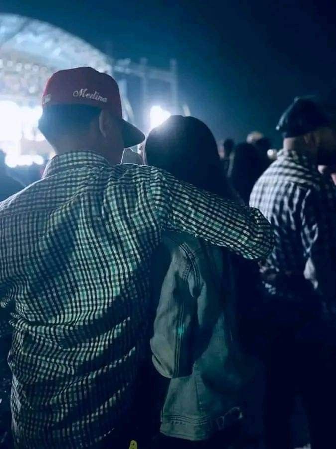 two people standing in front of an audience at a music festival with their arms around each other