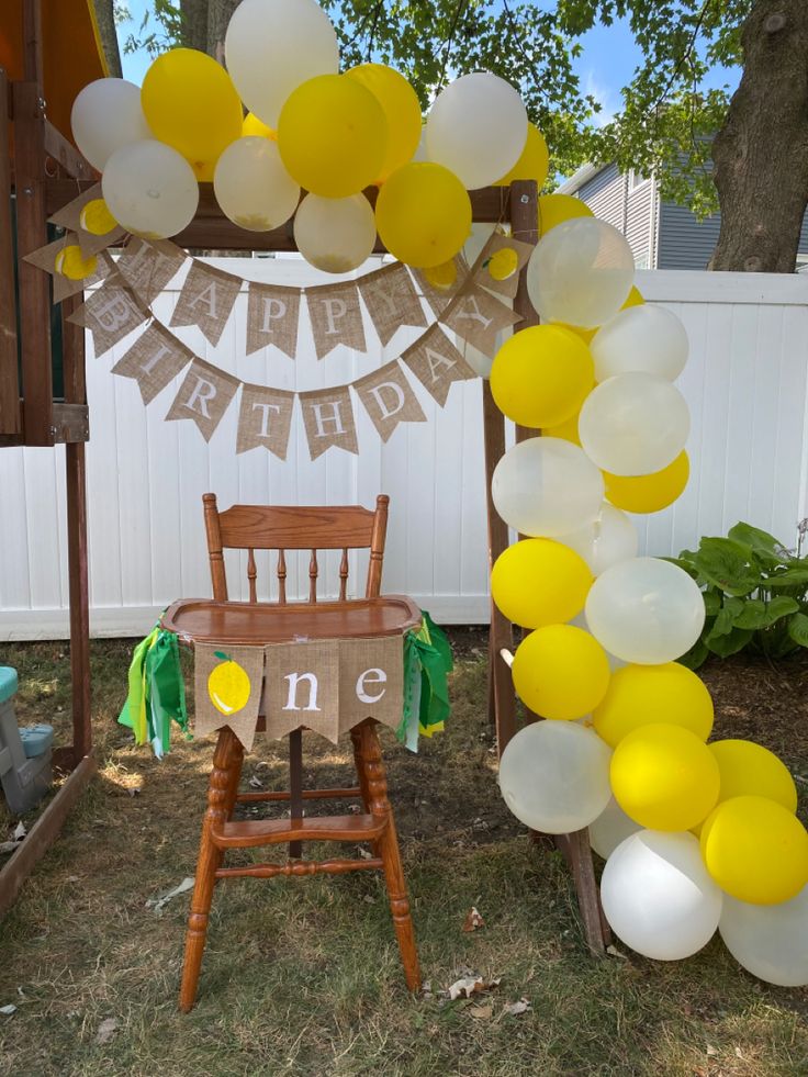 a chair under a yellow and white balloon arch