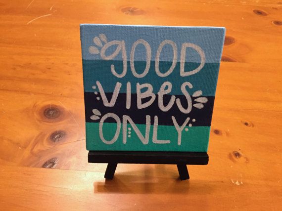 a small canvas with the words good vibes only on it sitting on a wooden table