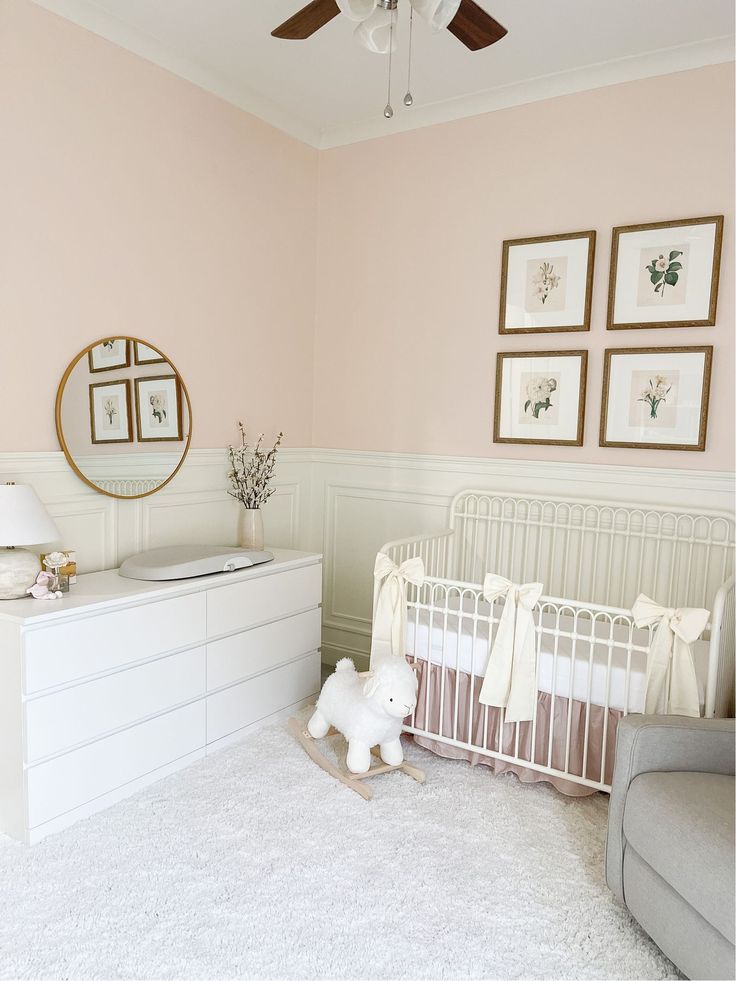 a baby's room with pink walls and white furniture