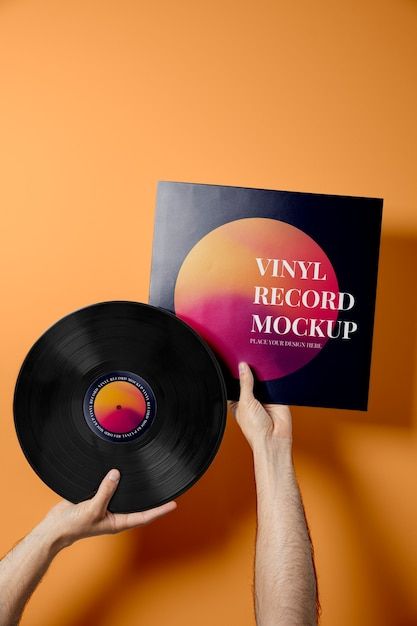 a person holding up a vinyl record in front of an orange wall with the words vinyl record mockup on it