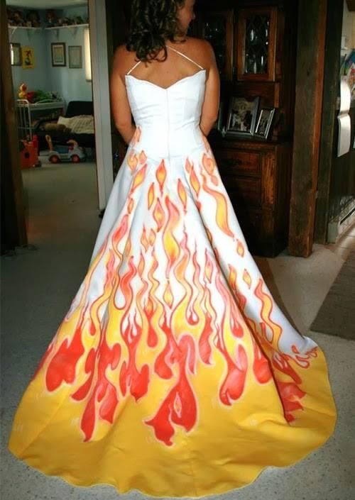 a woman in a dress with flames painted on it's side and back, standing next to a dresser