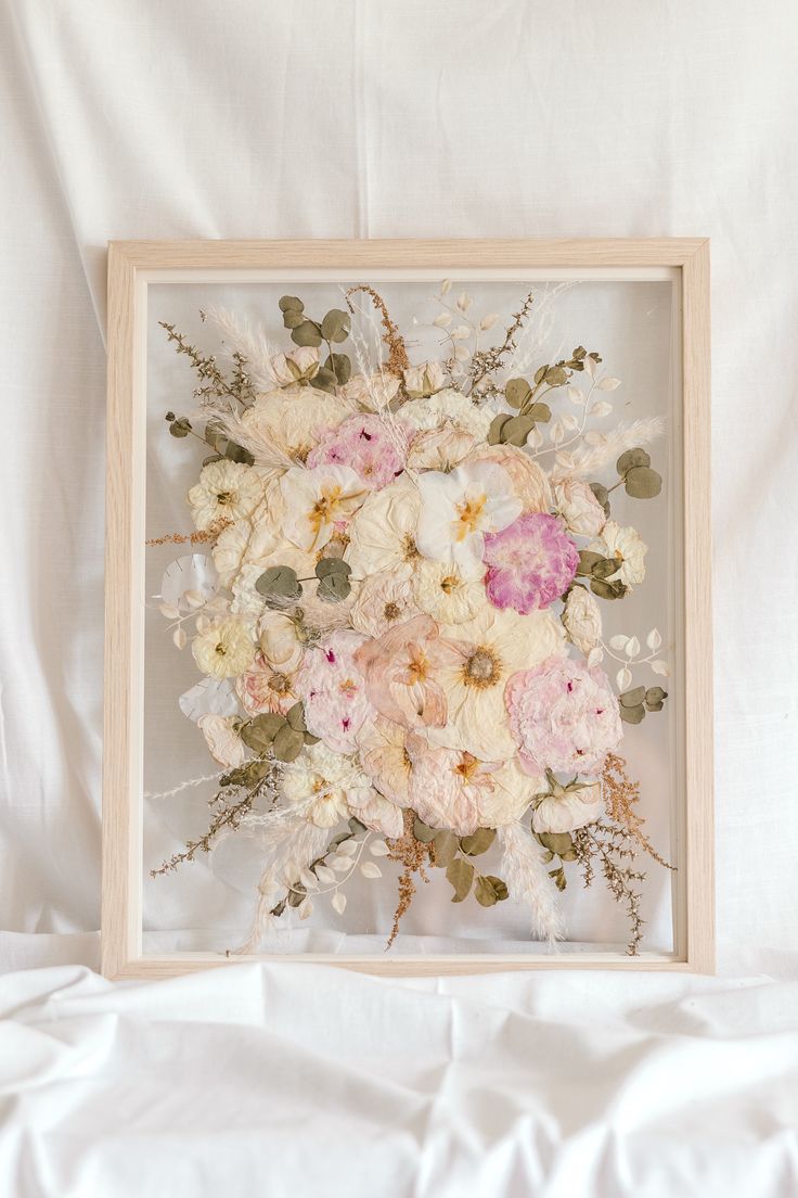 an arrangement of flowers in a wooden frame