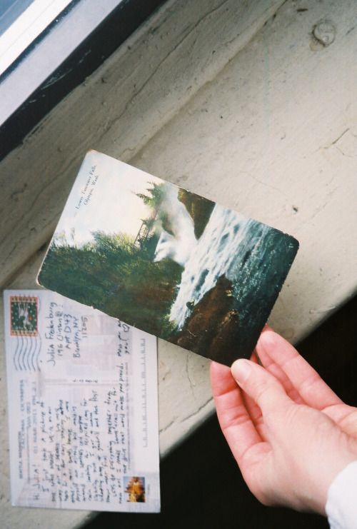 a person holding up a piece of paper next to a postcard