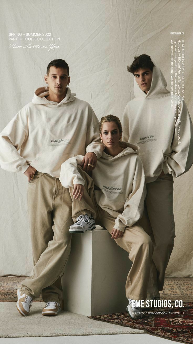 two men and a woman in white sweatshirts pose for the camera