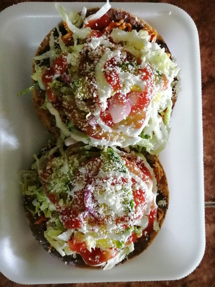 two open faced sandwiches covered in cheese and toppings on a white plate with a toothpick