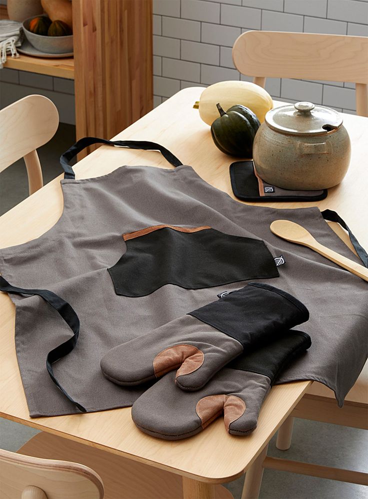 a kitchen table topped with an apron covered in black and brown fabric next to a tea pot