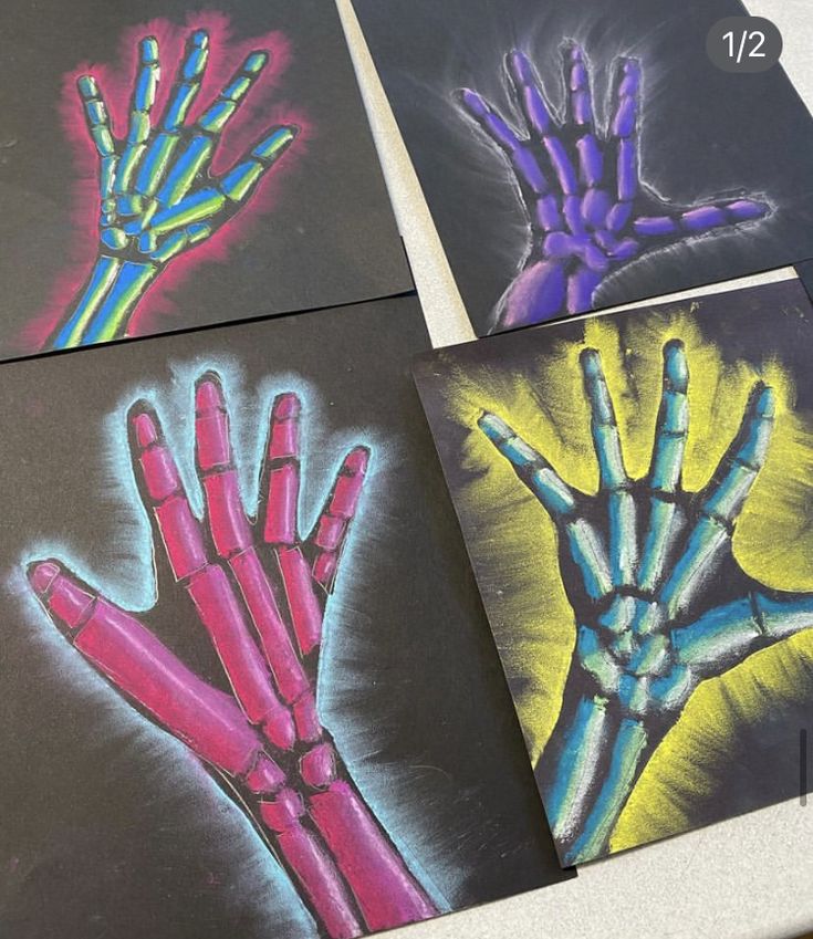 four different colored hand prints are shown on black paper with chalk pastel and crayons