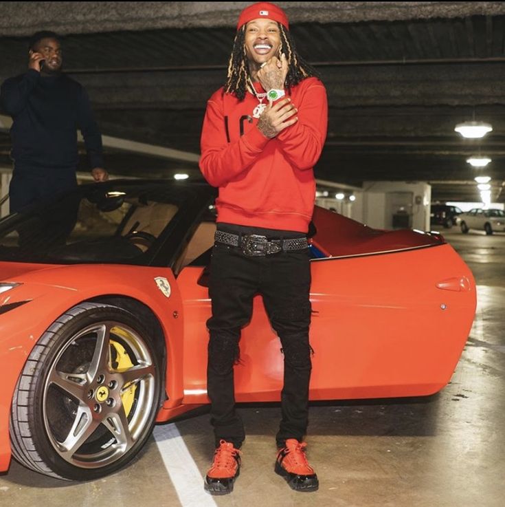 a man standing next to a red sports car