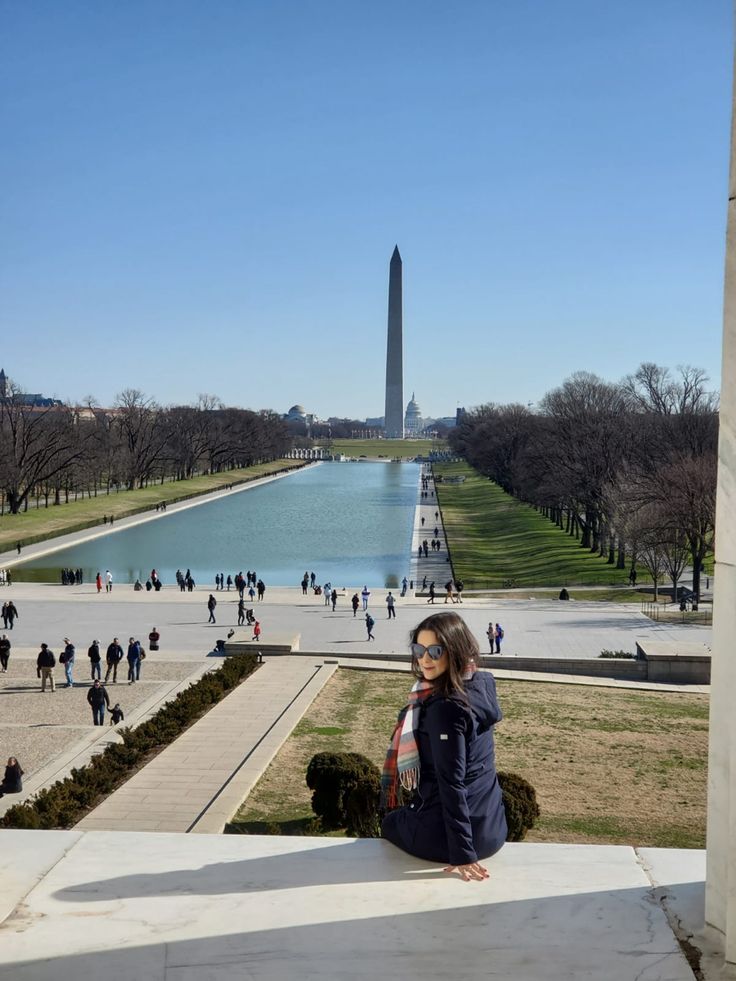 a woman sitting on the ground in front of a monument