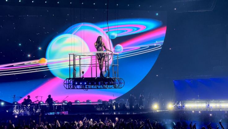 a woman standing on top of a platform in front of an audience at a concert