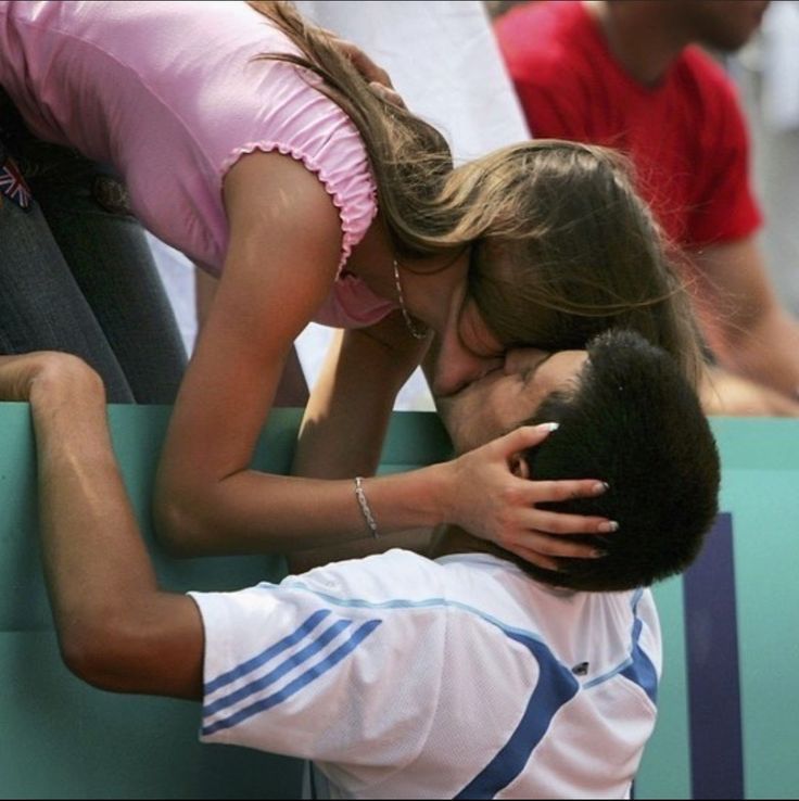 a man kissing a woman on the cheek at a tennis match