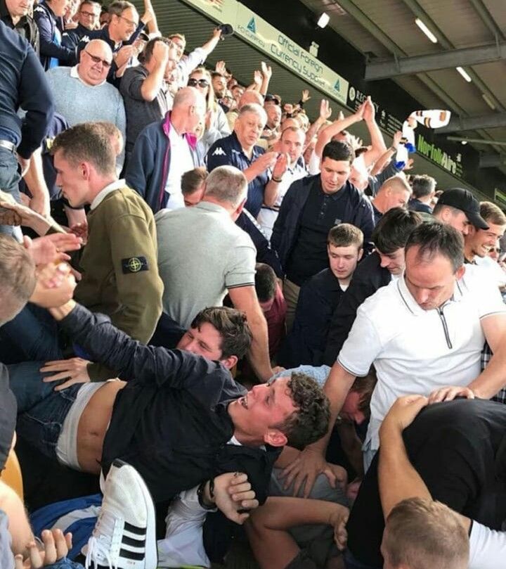 a group of men are huddled together in the stands at a sporting event with their hands up