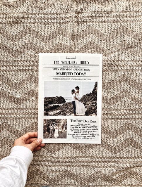 a person holding up a newspaper on top of a bed