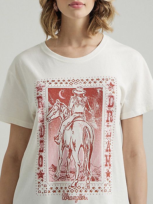 Wrangler Rodeo Dream Women's T-Shirt 100% Cotton Long Live Cowboys. Our Women's Wrangler Retro® Western Graphic Boyfriend Tee comes with a retro-inspired graphic that celebrates our Western heritage and those cowboys we love. It's crafted from a buttery soft cotton blend for comfort and cut with a boyfriend fit for a slightly oversized look that feels lived in and well-loved, no borrowing from the boys required. Fit: Boyfriend Sleeve Length: Short Neckline: Crew Neck Collar: Ribbed Western Style Relaxed Fit T-shirt With Screen Print, Western Style Relaxed Fit Graphic T-shirt, Western Style Relaxed Fit T-shirt With Graphic Print, Western White Top With Graphic Print, White Western Top With Graphic Print, White Western Tops With Graphic Print, White Graphic Print Top For Rodeo, Western White Crew Neck Tops, White Western Crew Neck Top