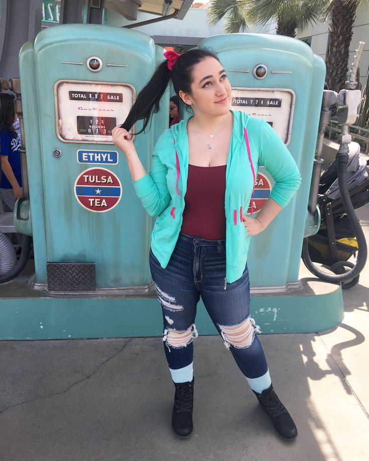 a woman standing in front of a gas pump with her hands on her hips and looking at the camera