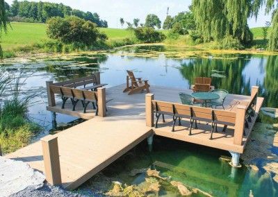 a wooden dock sitting next to a lake filled with lots of green plants and water