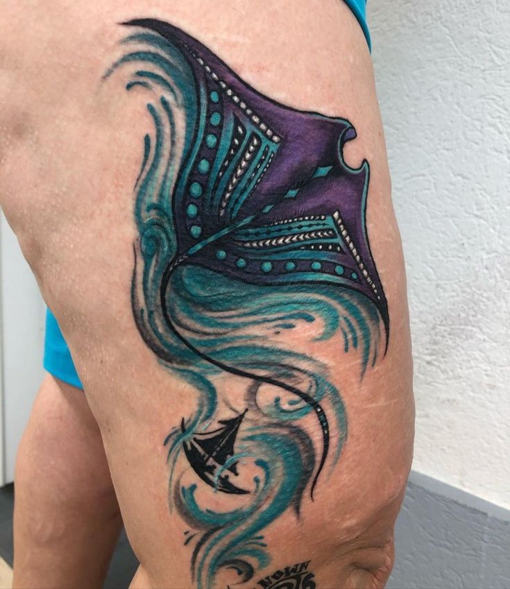 a woman's thigh with a blue and purple tattoo on it