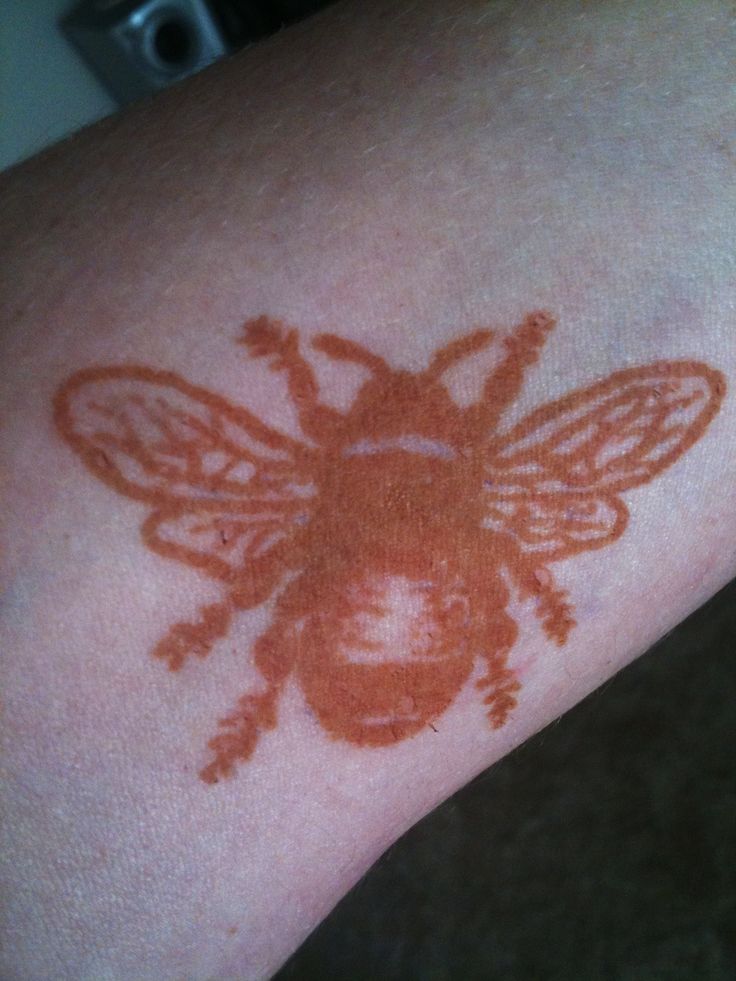 a close up of a person's arm with a tattoo on it that looks like a bee