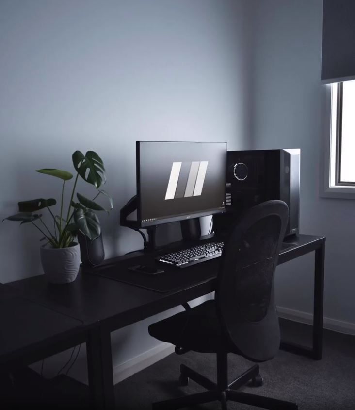 a desk with a computer, keyboard and monitor on it next to a potted plant