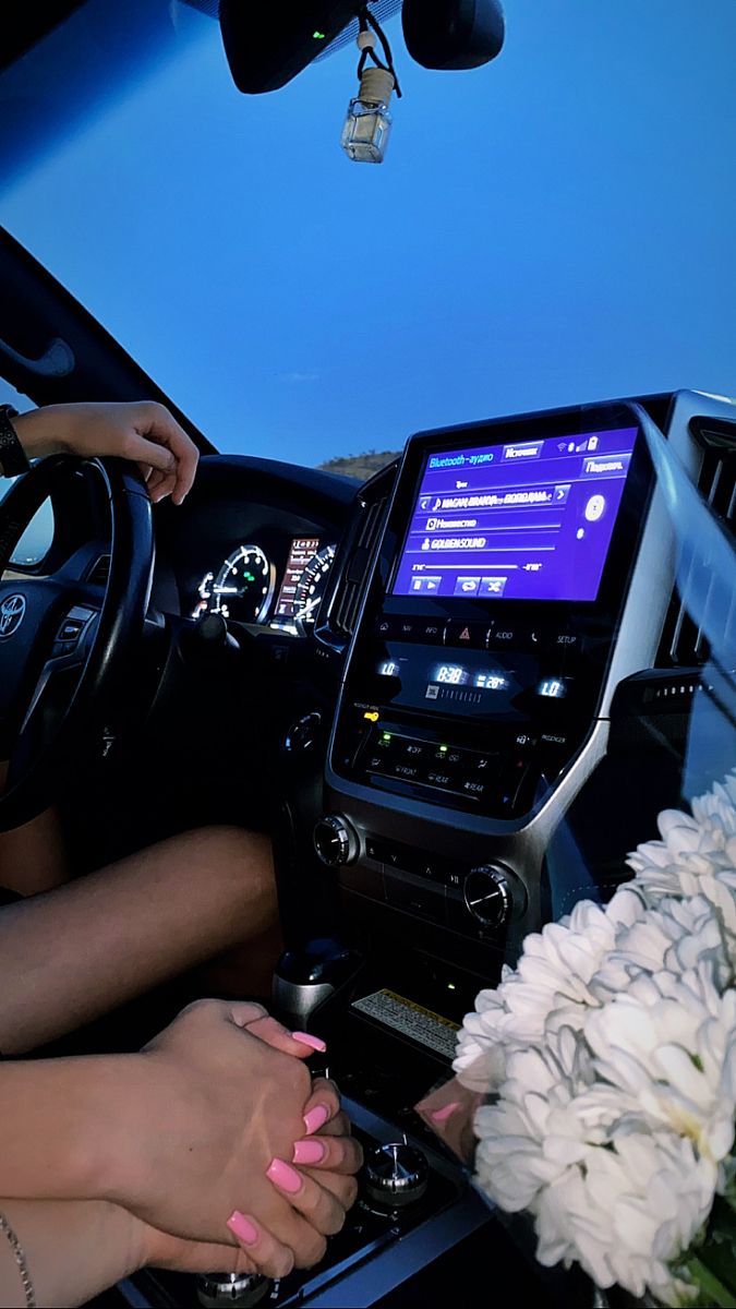 two people sitting in the driver's seat of a vehicle with flowers on the dashboard