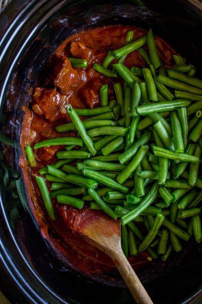 green beans are being cooked in the crockpot with meat and gravy