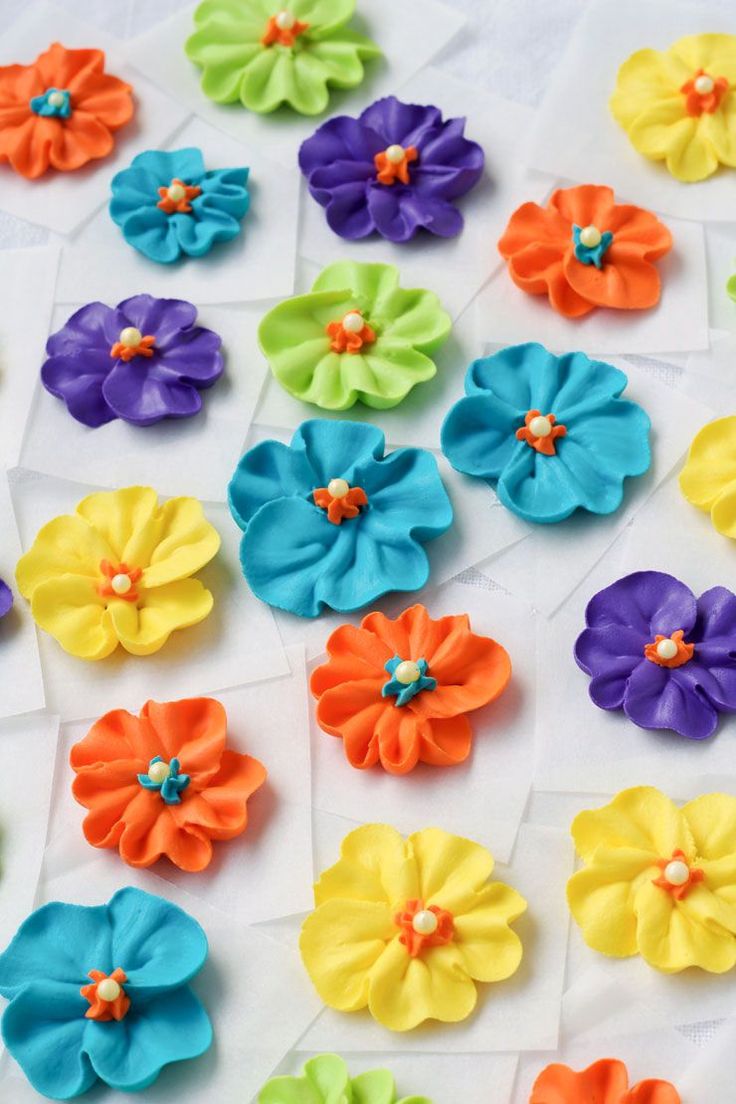 many different colored flowers on a white surface