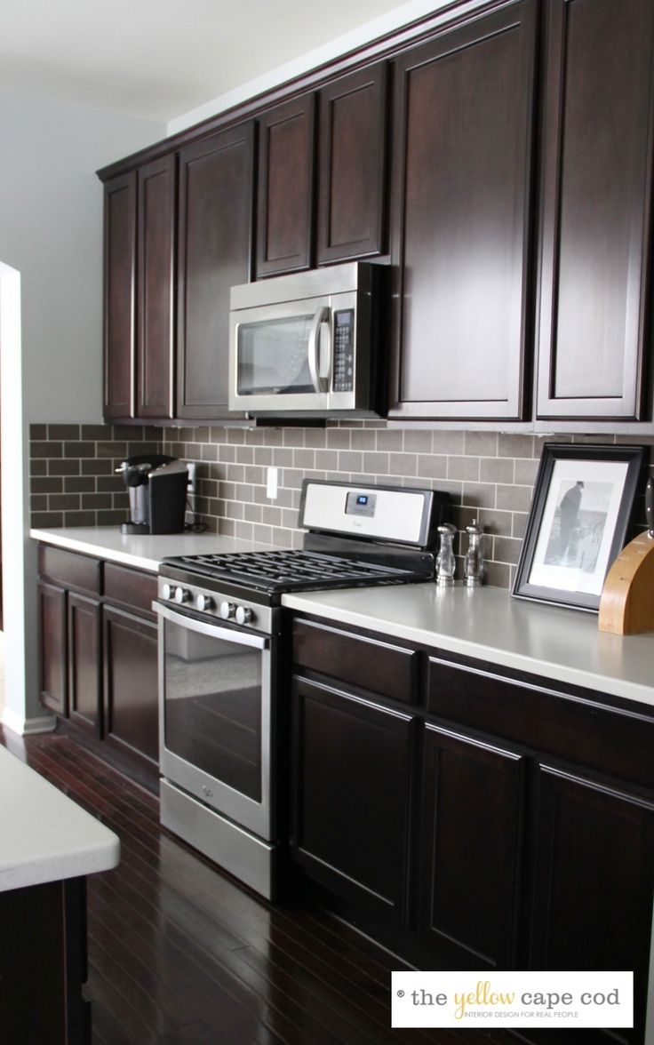 a kitchen with dark wood cabinets and white counter tops, stainless steel appliances and an oven