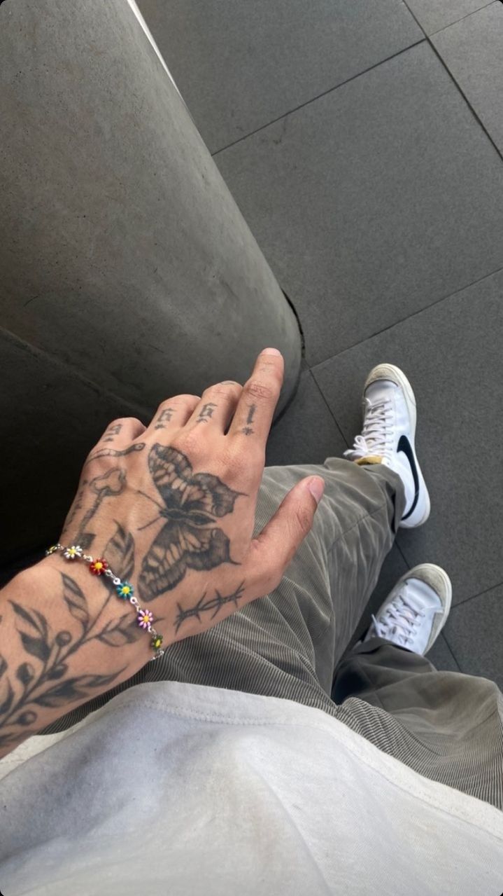 a person with tattoos on their arm sitting down and holding his hand up to the camera