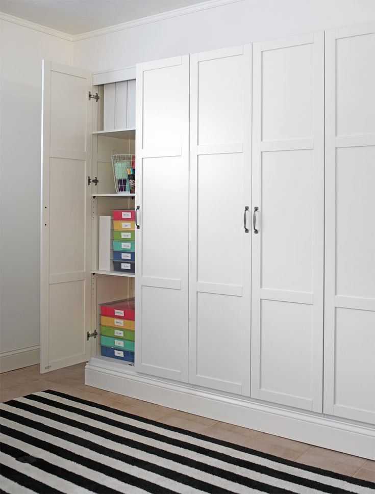 a room with white cabinets and black and white striped rug on the floor in front of it