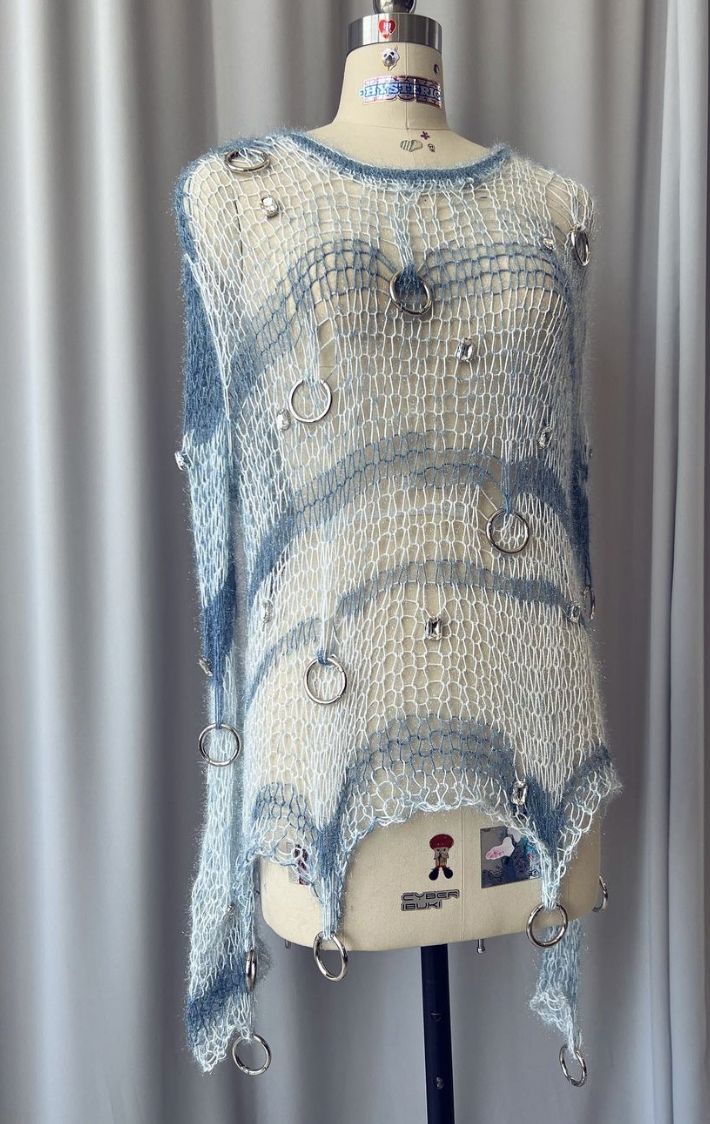 a white and blue sweater on a mannequin's head with silver buttons