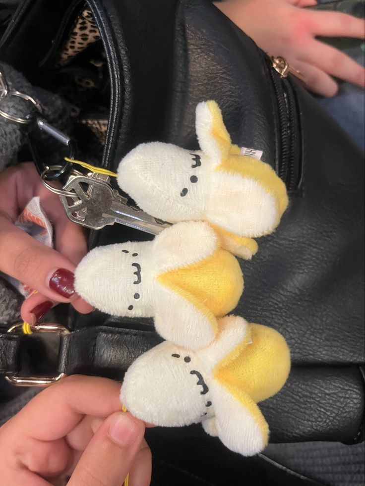 a person is holding a small stuffed animal in their hand and it's attached to the back of a purse