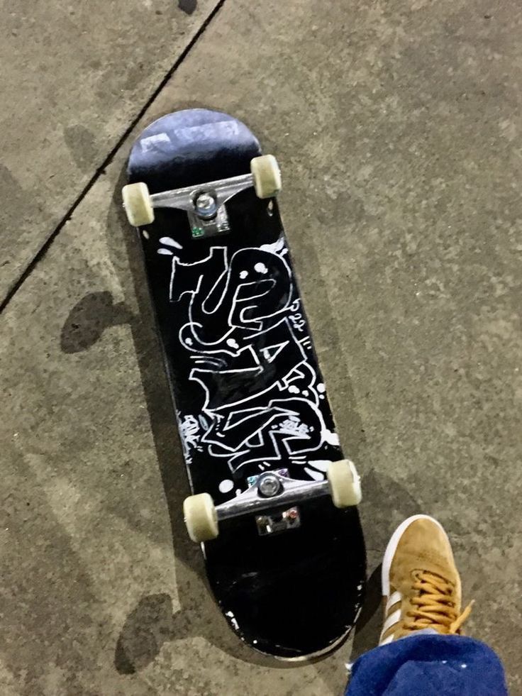 a person standing next to a skateboard with graffiti on it's back end