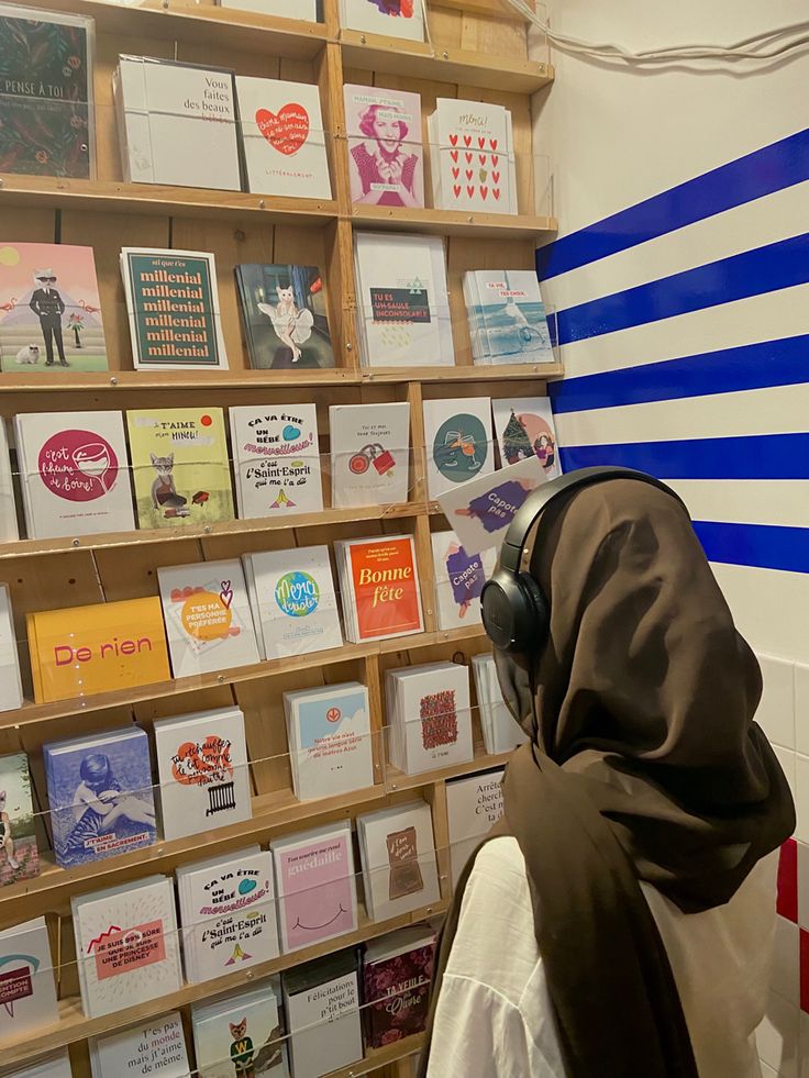 a person wearing a headscarf in front of a wall with greeting cards on it