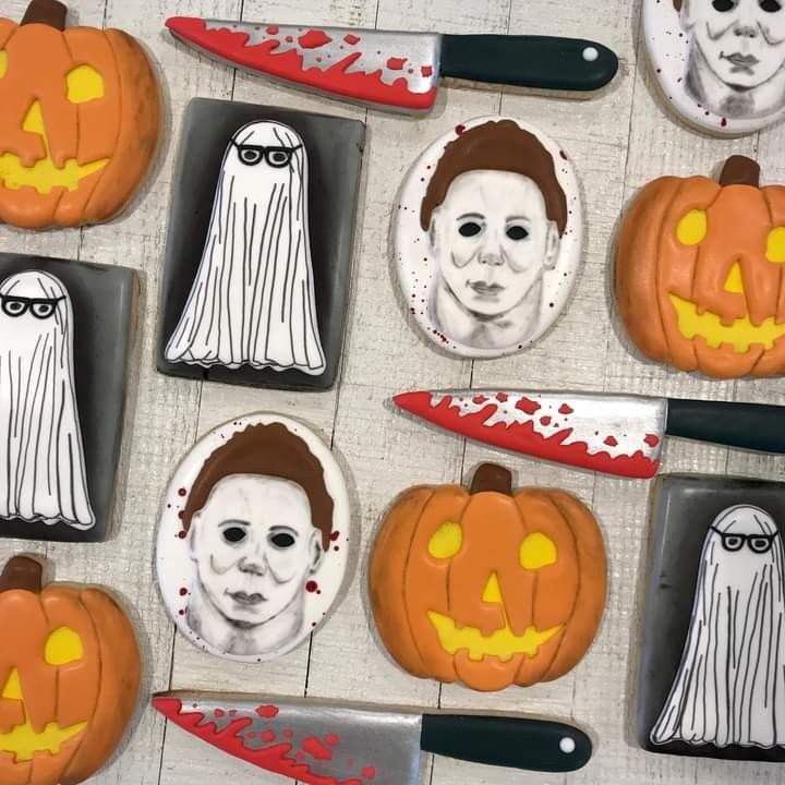 halloween cookies decorated with faces and decorations on a table next to knifes, forks and knives