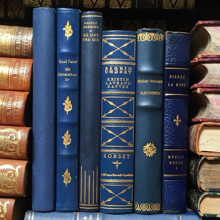 several blue books are stacked on top of each other in a bookcase with gold trimmings