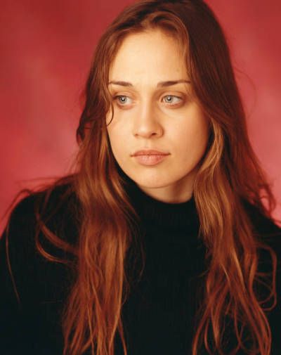 a woman with long brown hair wearing a black turtle neck sweater and looking at the camera