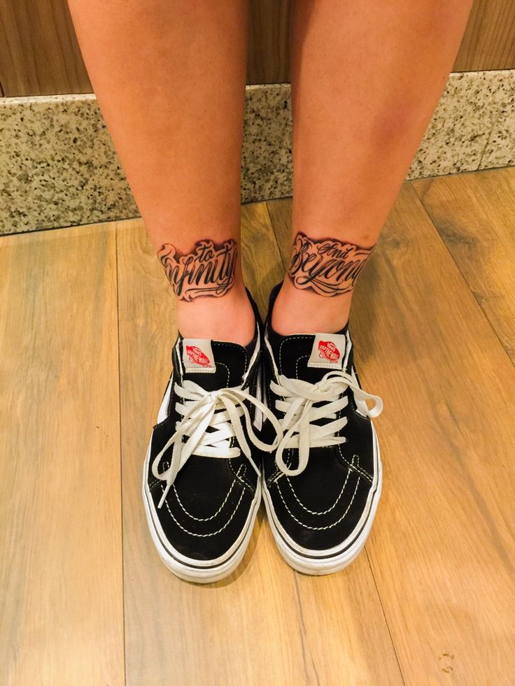 a woman's legs with tattoos on them and black shoes in front of a wall