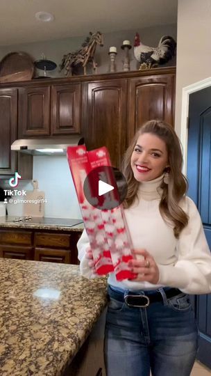 a woman standing in a kitchen holding a package