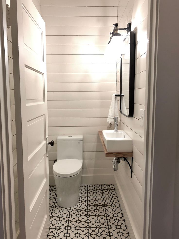 a white toilet sitting inside of a bathroom next to a sink and mirror on the wall