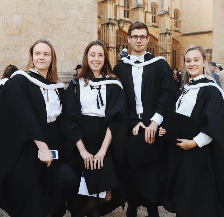 four people in graduation gowns posing for a photo