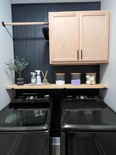 a washer and dryer in a laundry room with cabinets above them, next to each other