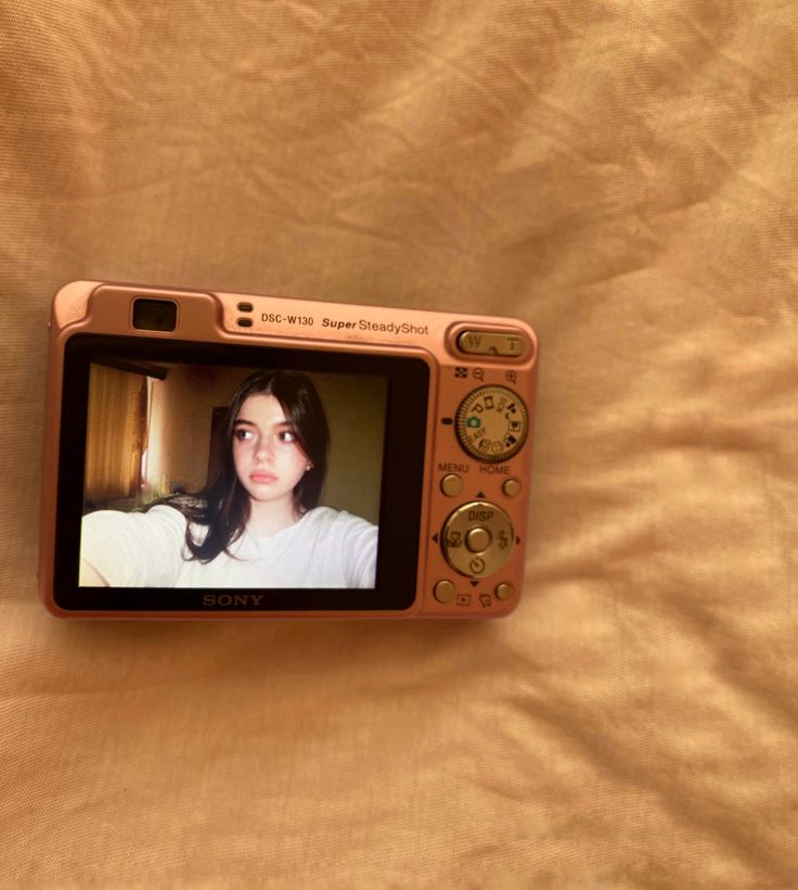 an orange camera with a woman's face on it sitting on top of a bed