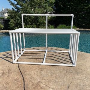 a white metal structure sitting on top of a rock next to a pool