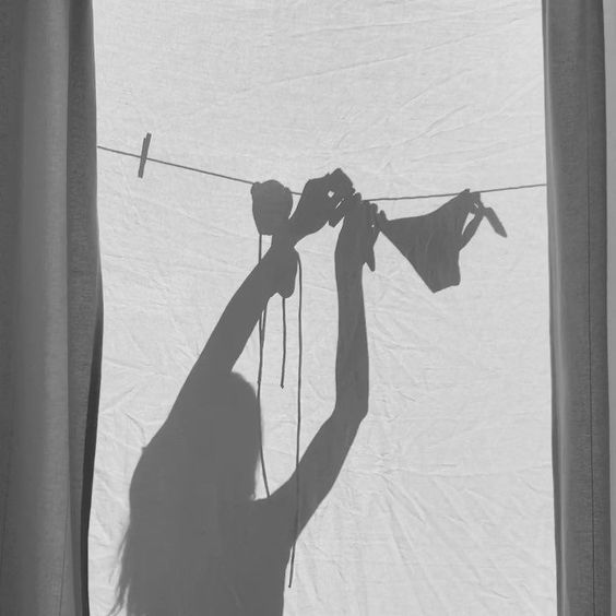 the shadow of a person hanging on a clothes line with their hands and feet in front of them