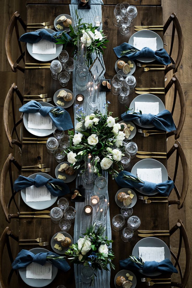 the table is set with white flowers and blue napkins